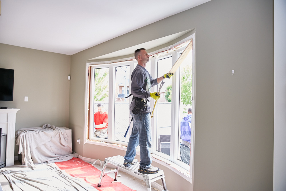 Contractor installing a large replacement window in a home